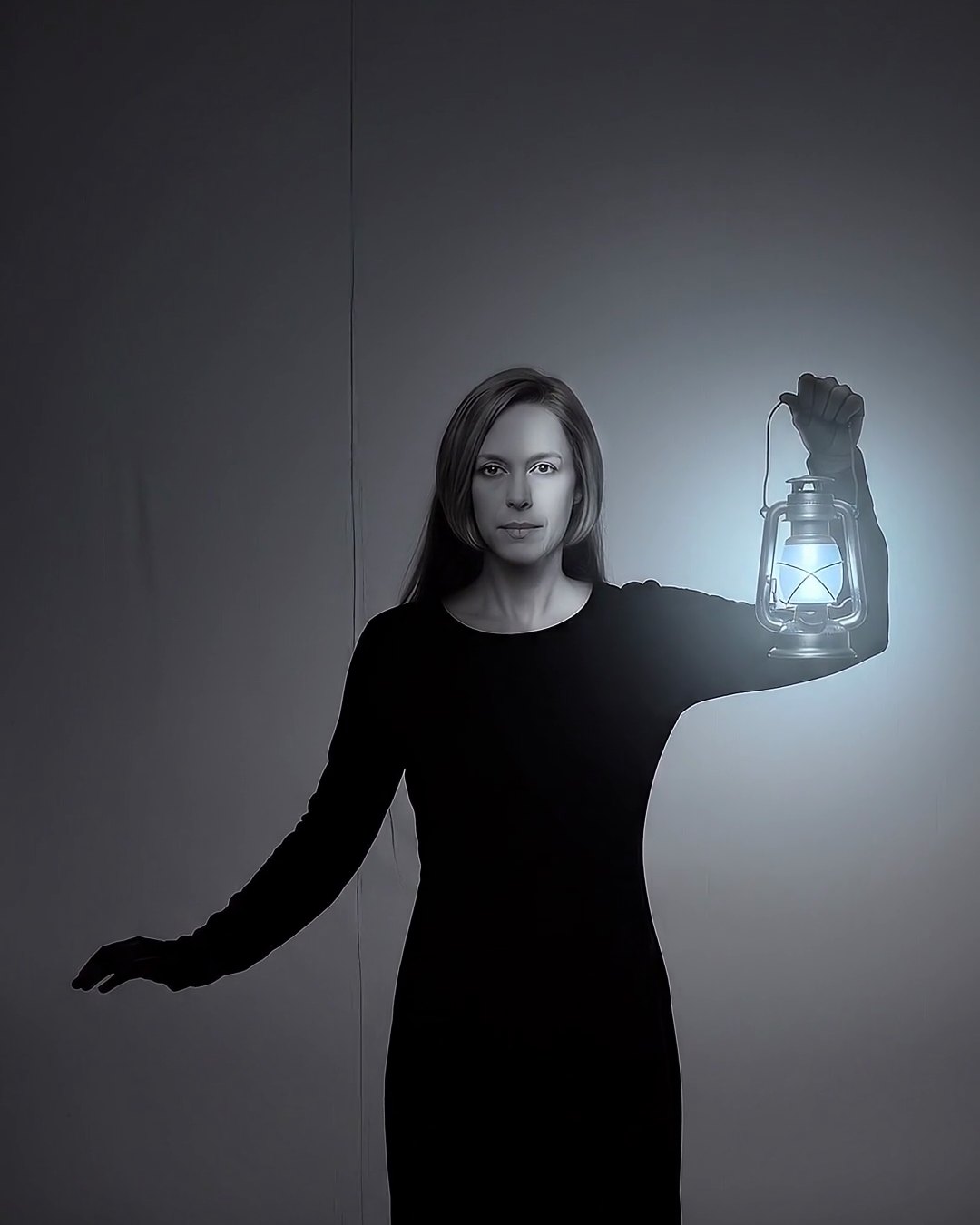 A woman in a black dress holding up a pale blue lantern